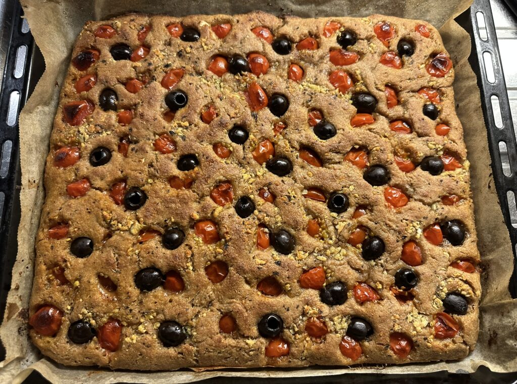 Peltileipä jonka täytteenä valkosipulimurskaa, oliiveja ja kirsikkatomaatteja.
