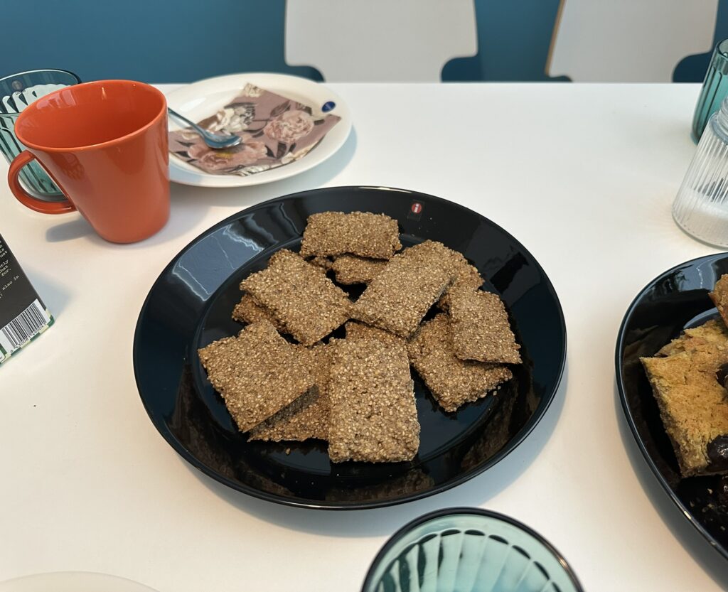 Seesaminsiemenkeksejä mustalla lautasella kahvipöydässä.