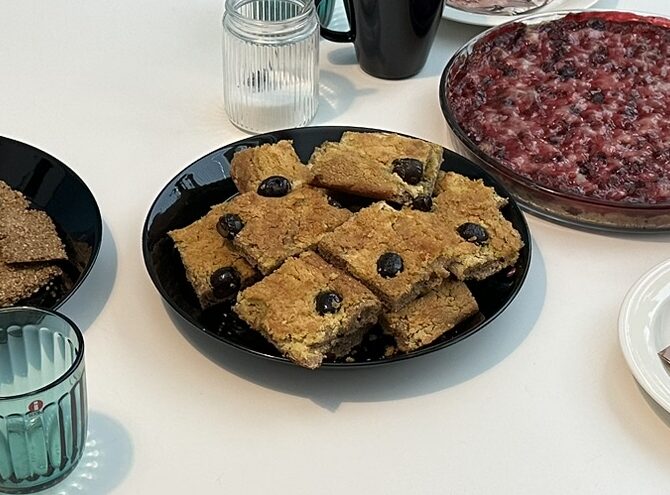 Mustalla lautasella kahvipöydässä hummuksella ja oliiveilla päällystettyjä peltileivän paloja.